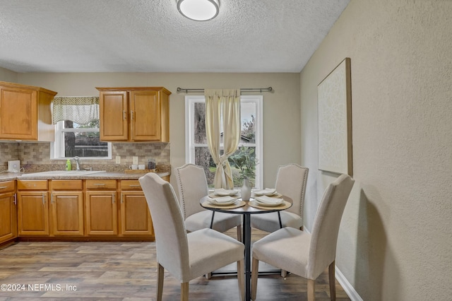 dining area featuring a textured ceiling, wood finished floors, and a textured wall