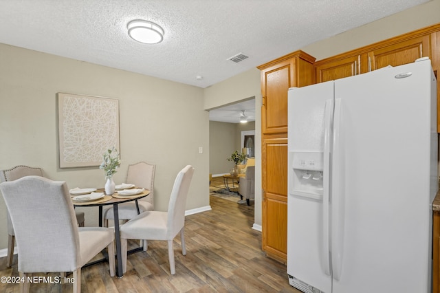 dining space featuring baseboards, wood finished floors, visible vents, and a textured ceiling