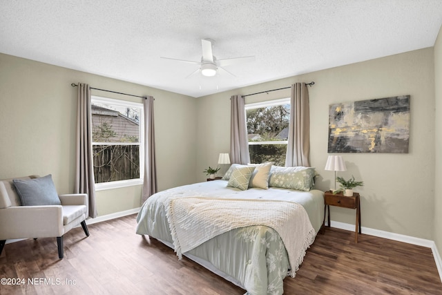 bedroom with a ceiling fan, wood finished floors, baseboards, and a textured ceiling