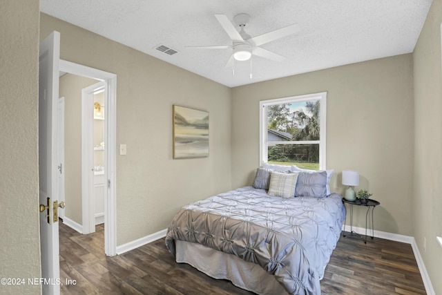 bedroom with visible vents, baseboards, a textured ceiling, and wood finished floors