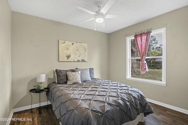 bedroom with a textured ceiling, baseboards, and wood finished floors