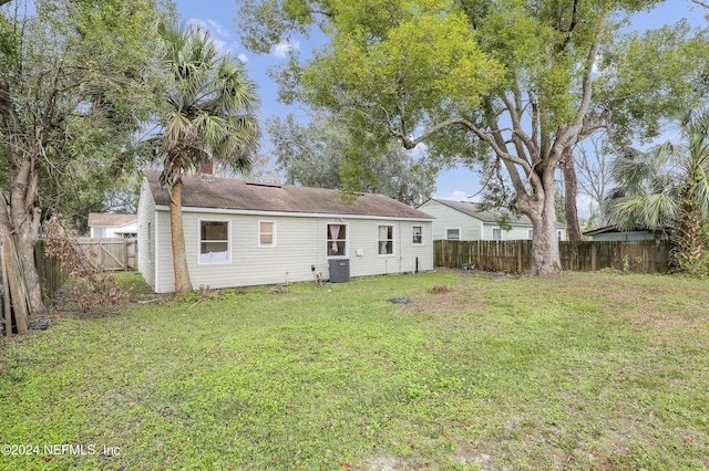 rear view of property featuring cooling unit, a lawn, and a fenced backyard