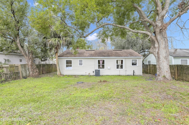 rear view of house with a yard, cooling unit, and a fenced backyard