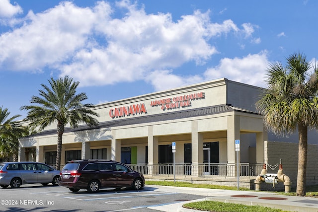 view of building exterior with fence and uncovered parking