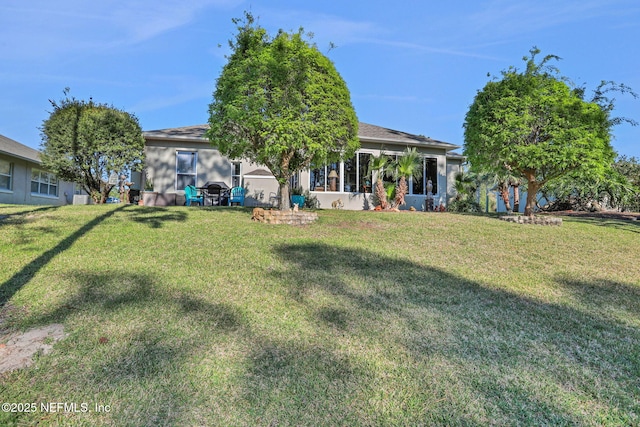 back of property with a lawn and stucco siding