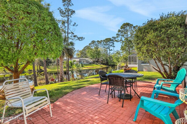 view of patio / terrace featuring a lanai, outdoor dining area, and a water view