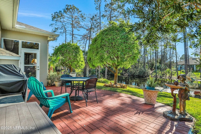 wooden deck with outdoor dining space, a patio, a water view, and a grill