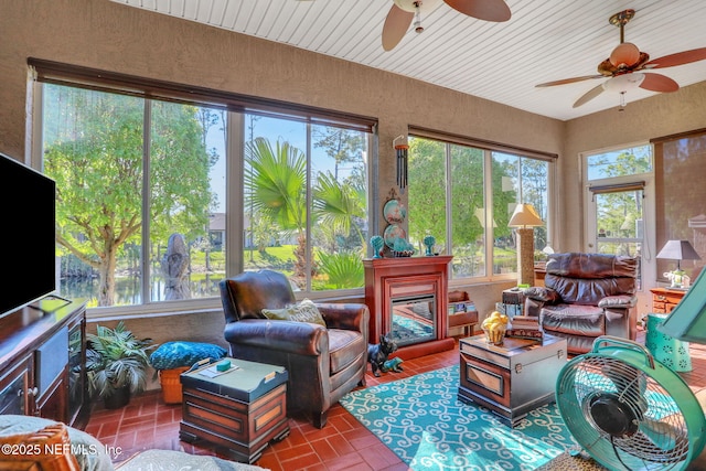 living area featuring brick floor, wood ceiling, a ceiling fan, and a textured wall