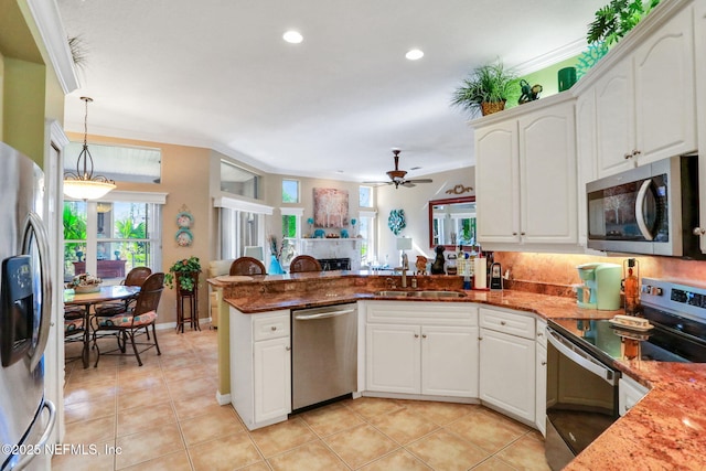 kitchen with a sink, stainless steel appliances, a peninsula, light tile patterned flooring, and a fireplace