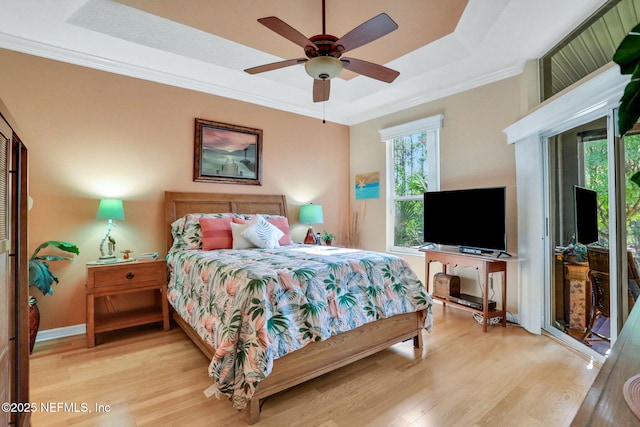 bedroom featuring a raised ceiling, wood finished floors, crown molding, and access to outside