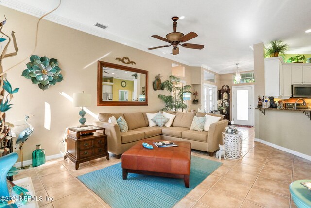 living area featuring light tile patterned floors, baseboards, visible vents, and ornamental molding