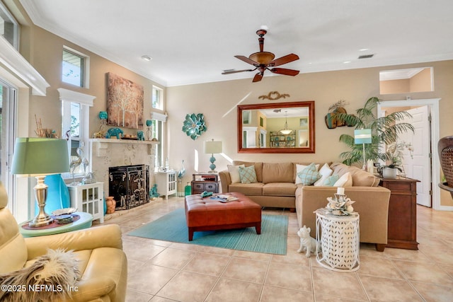 living area with tile patterned floors, visible vents, a ceiling fan, crown molding, and a premium fireplace