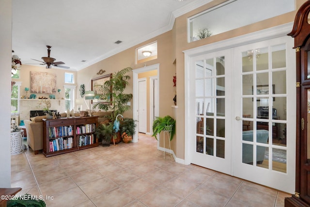 entrance foyer featuring a fireplace, crown molding, light tile patterned floors, and french doors