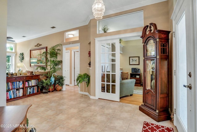 foyer with a notable chandelier, ornamental molding, french doors, light tile patterned flooring, and baseboards