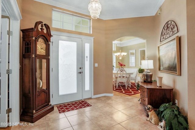 entrance foyer featuring arched walkways, light tile patterned floors, crown molding, and an inviting chandelier