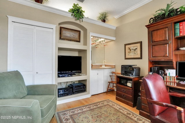 office with built in features, light wood-style flooring, and crown molding