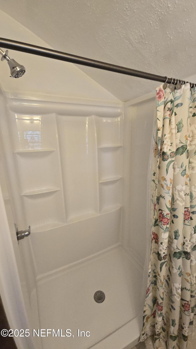 bathroom featuring a textured ceiling and a shower stall