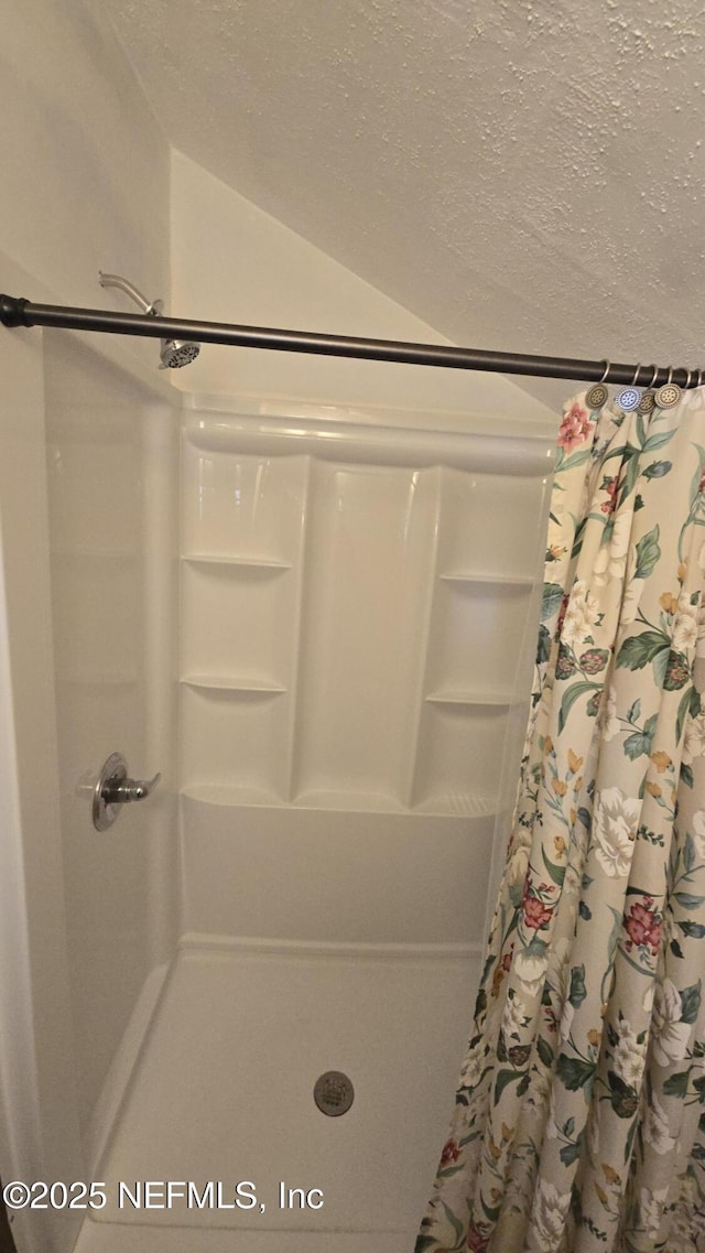 full bathroom with lofted ceiling, a shower with curtain, and a textured ceiling