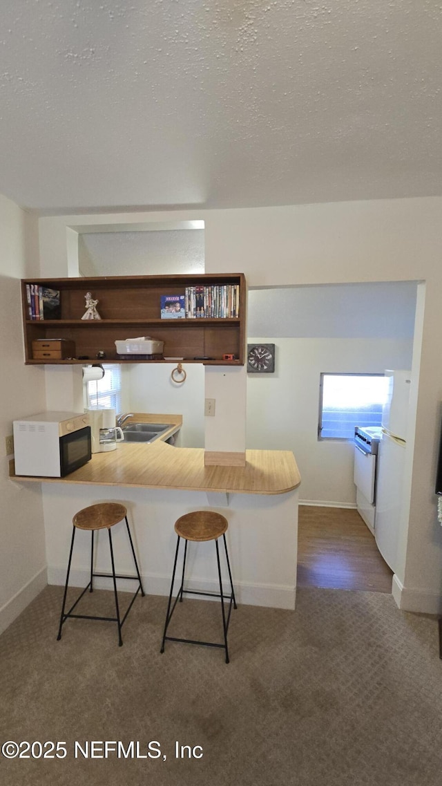 kitchen featuring carpet flooring, a sink, a textured ceiling, and open shelves