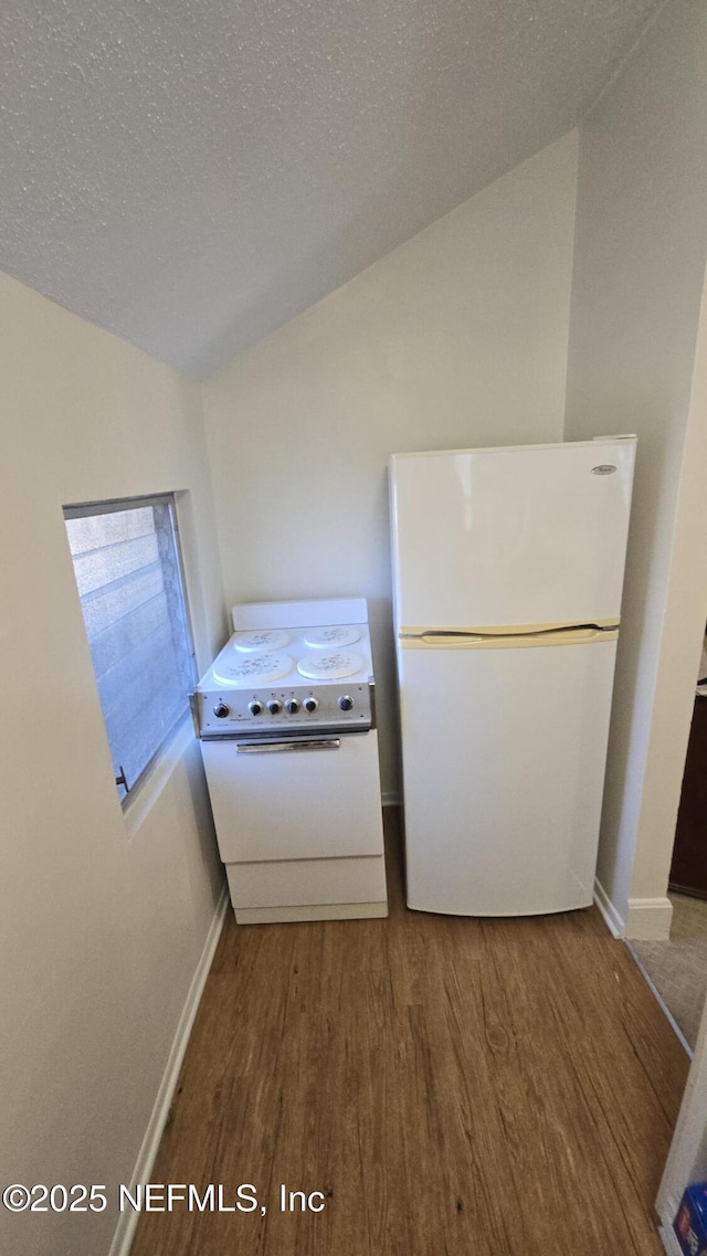 kitchen featuring white appliances, wood finished floors, a textured ceiling, and vaulted ceiling