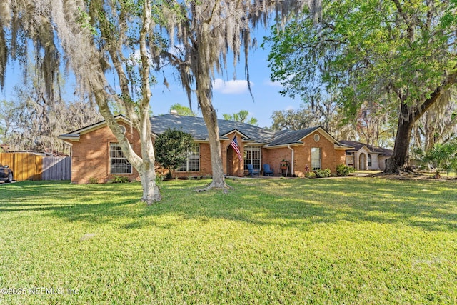 ranch-style house featuring brick siding, a front lawn, and fence