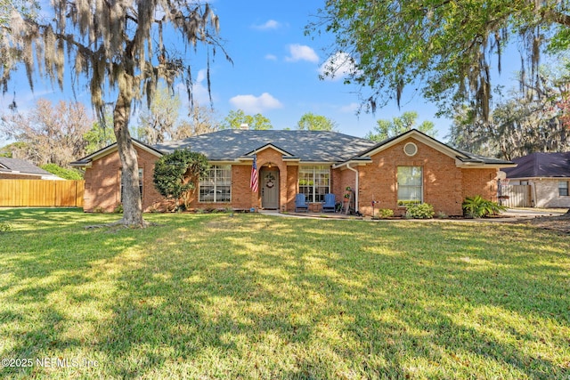 ranch-style house featuring a front lawn, fence, and brick siding