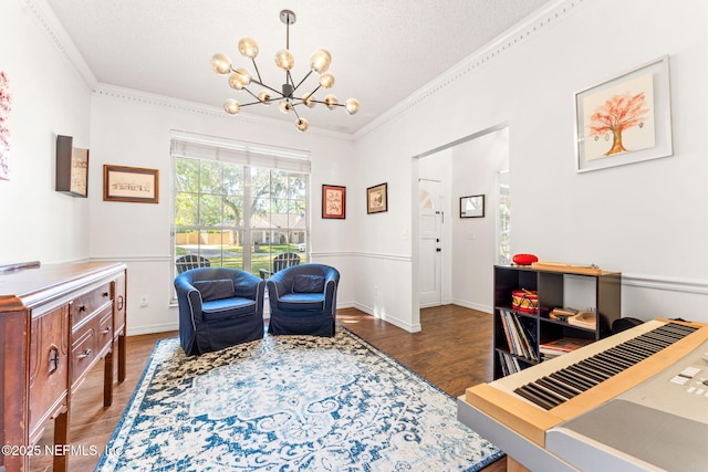 sitting room with wood finished floors, baseboards, ornamental molding, a textured ceiling, and a notable chandelier