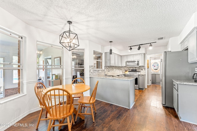 dining space featuring visible vents, a textured ceiling, an inviting chandelier, and dark wood finished floors