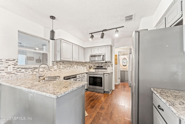 kitchen with visible vents, a peninsula, a sink, decorative backsplash, and stainless steel appliances