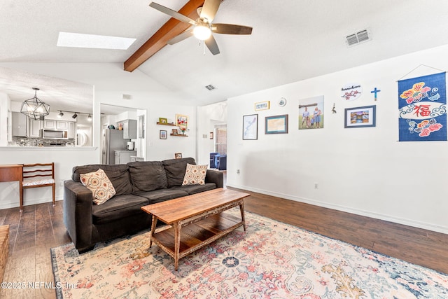 living area with visible vents, baseboards, lofted ceiling with skylight, hardwood / wood-style floors, and ceiling fan with notable chandelier