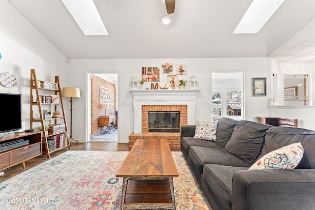 living room with wood finished floors, vaulted ceiling with skylight, a fireplace, and a textured ceiling