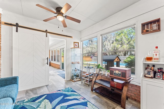 sunroom with a barn door and ceiling fan