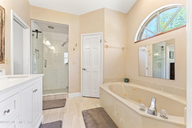 full bathroom with a tub with jets, a stall shower, and vanity