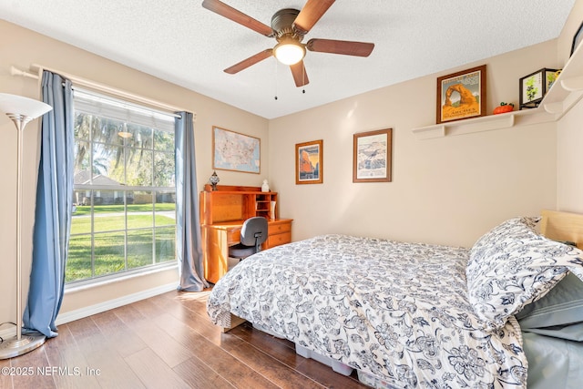 bedroom with baseboards, a textured ceiling, wood finished floors, and a ceiling fan