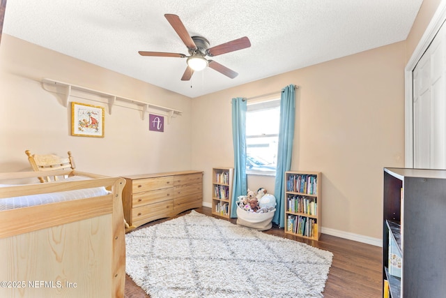 bedroom with ceiling fan, wood finished floors, baseboards, and a textured ceiling