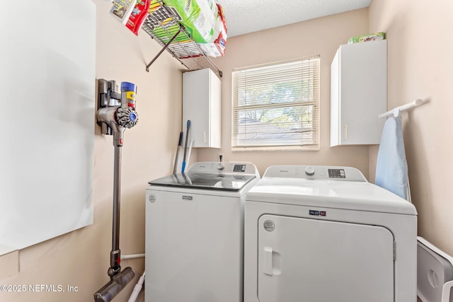 laundry room with washing machine and dryer, cabinet space, and a textured ceiling