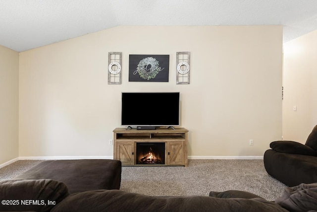 living room with a lit fireplace, carpet flooring, baseboards, and lofted ceiling