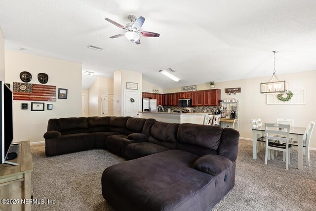 carpeted living area featuring visible vents, ceiling fan with notable chandelier, baseboards, and vaulted ceiling