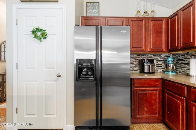 kitchen featuring decorative backsplash, dark brown cabinets, and stainless steel refrigerator with ice dispenser