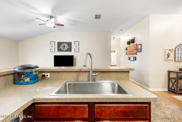 kitchen with a ceiling fan, visible vents, lofted ceiling, a sink, and light countertops