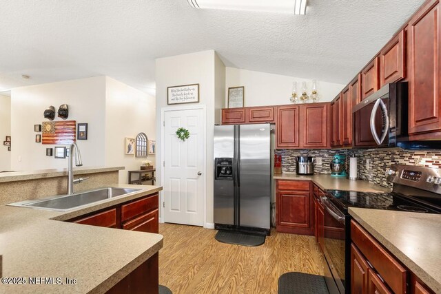 kitchen with a sink, light wood-type flooring, decorative backsplash, appliances with stainless steel finishes, and reddish brown cabinets