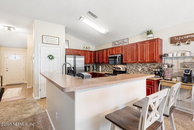 kitchen with visible vents, light countertops, vaulted ceiling, appliances with stainless steel finishes, and backsplash