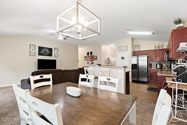 dining room with ceiling fan with notable chandelier and lofted ceiling