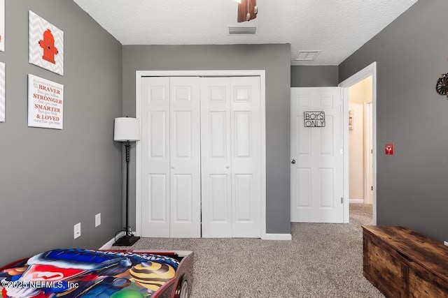 bedroom featuring baseboards, visible vents, a closet, a textured ceiling, and carpet flooring