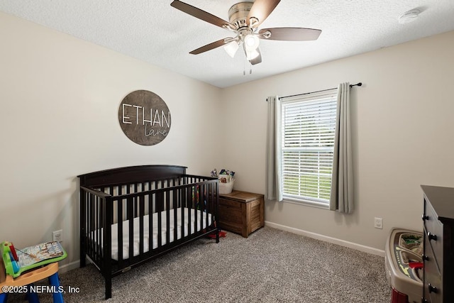 carpeted bedroom with a nursery area, a textured ceiling, baseboards, and a ceiling fan