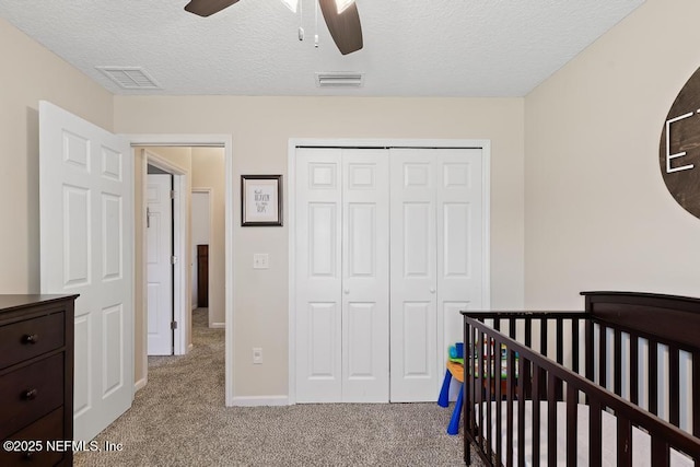 bedroom featuring carpet flooring, visible vents, a closet, and a textured ceiling