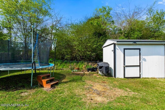 view of yard featuring a storage shed, an outbuilding, a trampoline, and fence