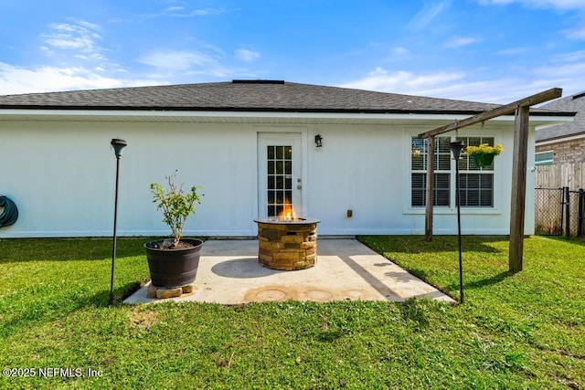 rear view of house featuring a patio, a shingled roof, a yard, and fence