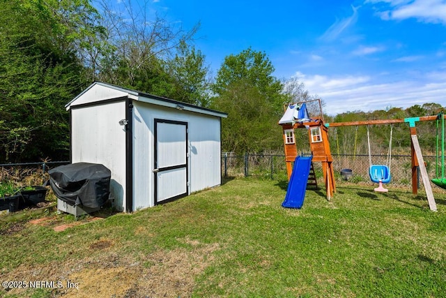 view of playground featuring an outbuilding, a lawn, fence, and a shed