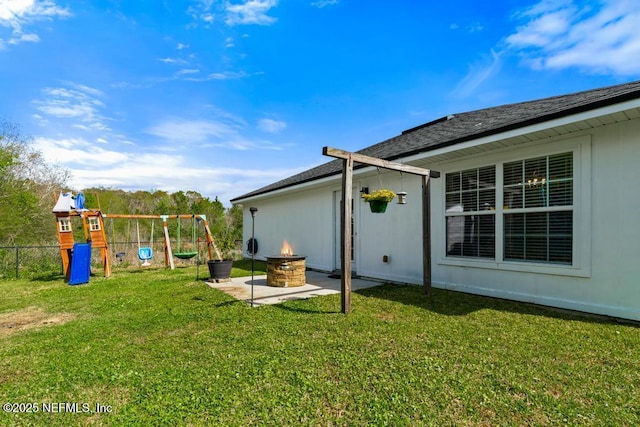 view of yard with a patio, a playground, a fire pit, and fence